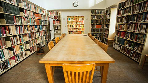 View into the room with an empty table and bookshelves on either side.