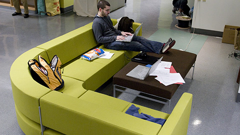 One student working while sitting at a large curved couch. 