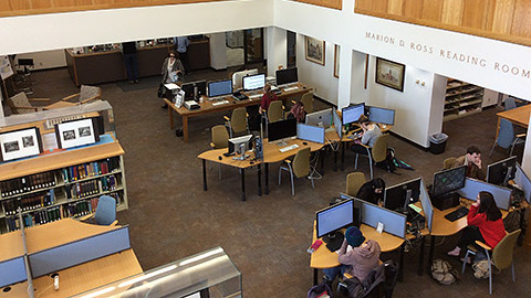 Overhead view of students working at computers with bookshelves on the other side of the room.