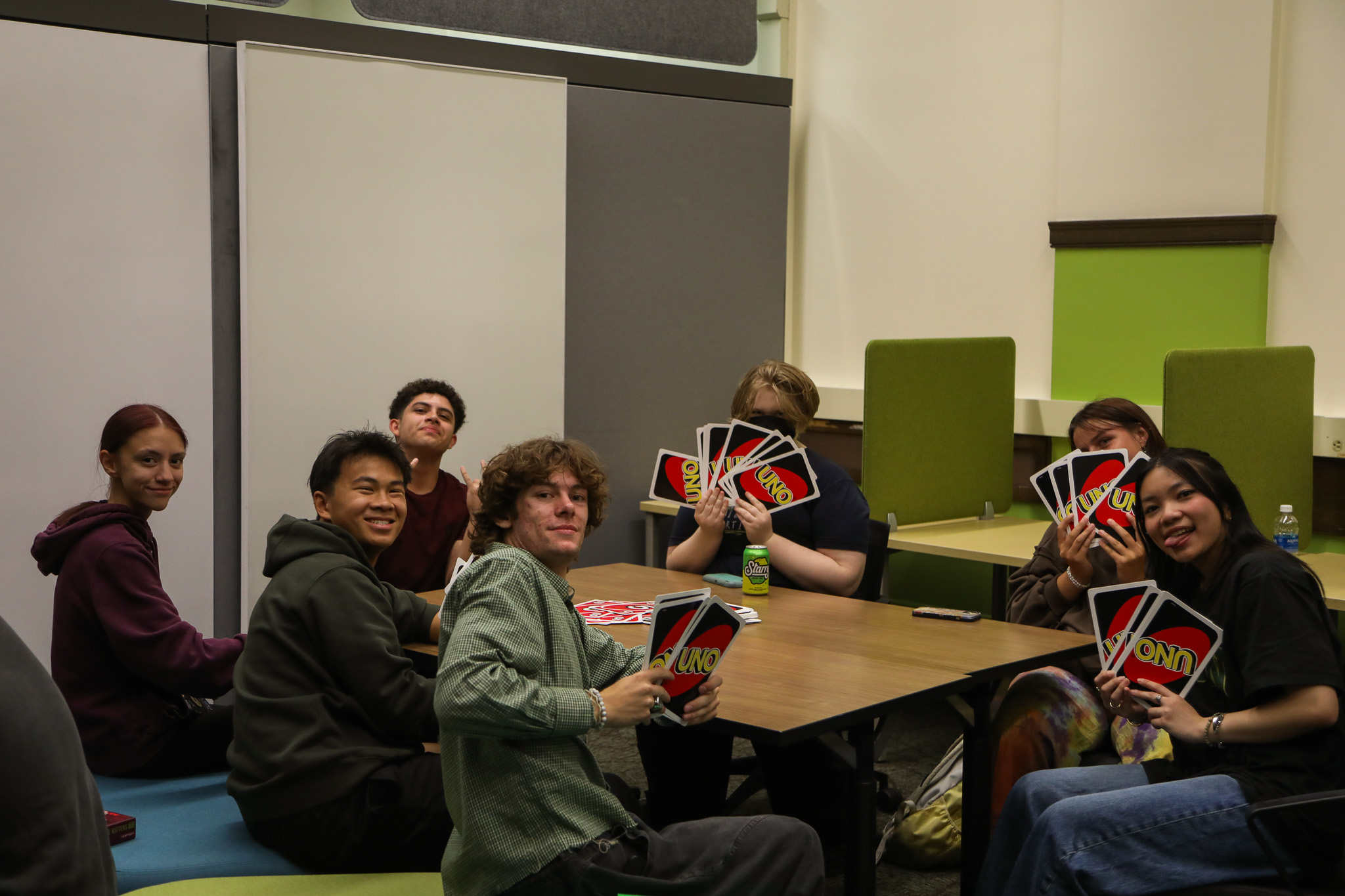 Group of seven male and female students playing UNO card game.