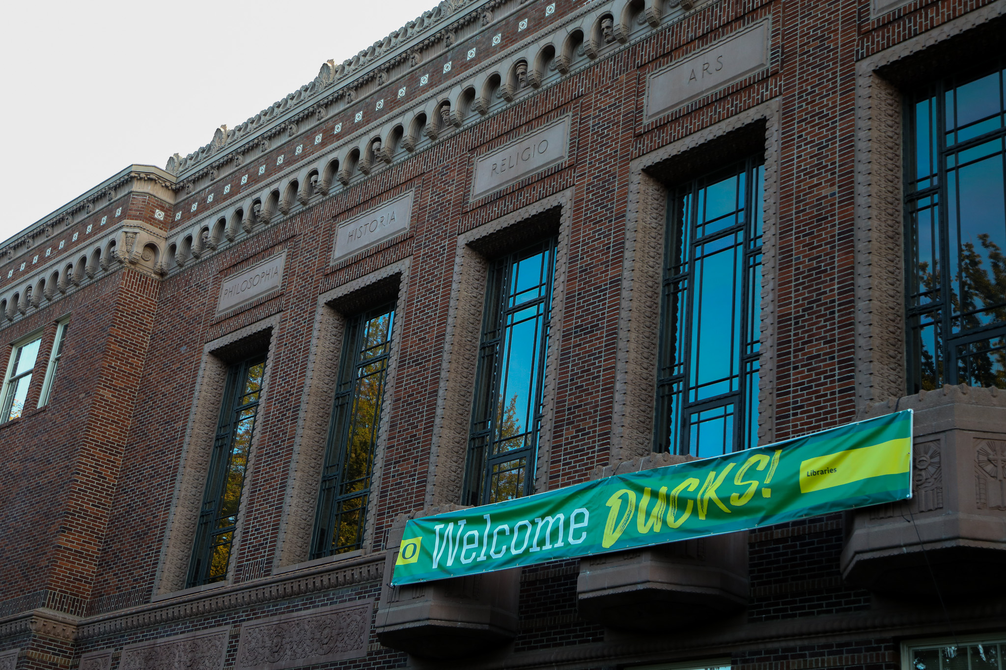 A sign reading "Welcome Ducks" hangs above the entrance of Knight Library.