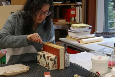 Victoria Wong repairing the spine of an old book in the UO Libraries' Beach Conservation Lab