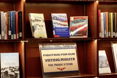 Display bookshelves in Knight Library hold many books and a sign that reads, "Fighting for Our Voting Rights."