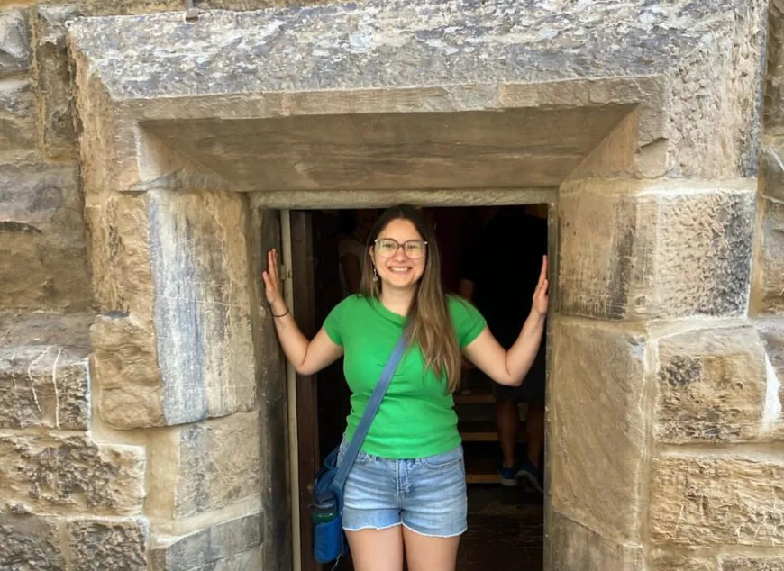 Liesl Cohn standing in doorway of a stone masonry building.