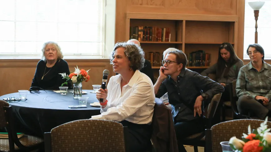 woman with mic at a table with other people asks a question