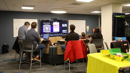 Faculty in the DREAM Lab, display screen says "Data Cartels" 