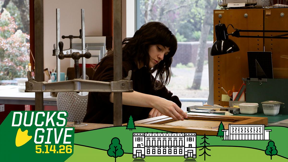 Student worker cleaning the back on a canvas painting on a bench in the Beach Conservation Lab