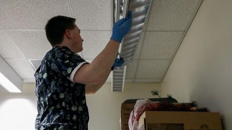 Ryan Robertson replaces lightbulbs in ceiling fixtures