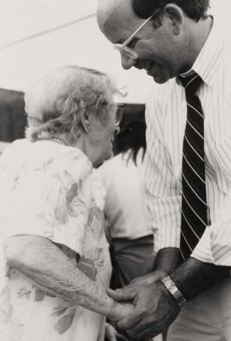 Peter DeFazio holding the hand of an elderly woman.