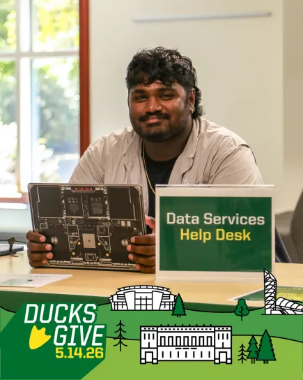 Student worker Vikram Thirumaran sitting at the Data Services Help Desk with open laptop computer