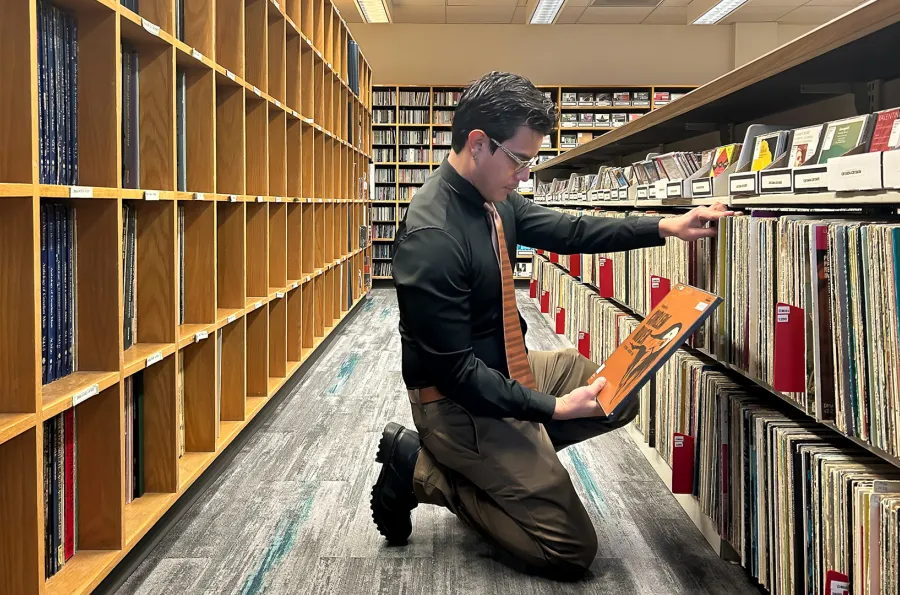 A person kneeling looking at vinyl records