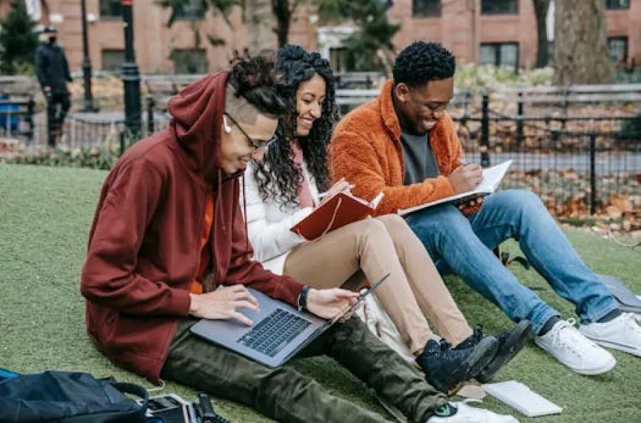 Three college students studying on a campus green. 