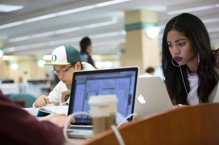 Students working on laptops in the library. 