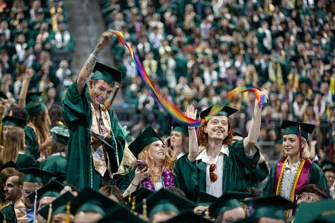 Two graduates holding a rainbow banner during the commencement ceremony
