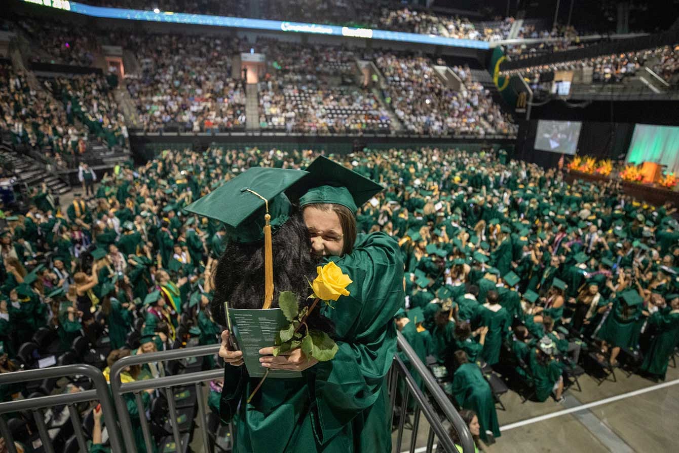 Two gradutes hugging in the stands during the commencement ceremony