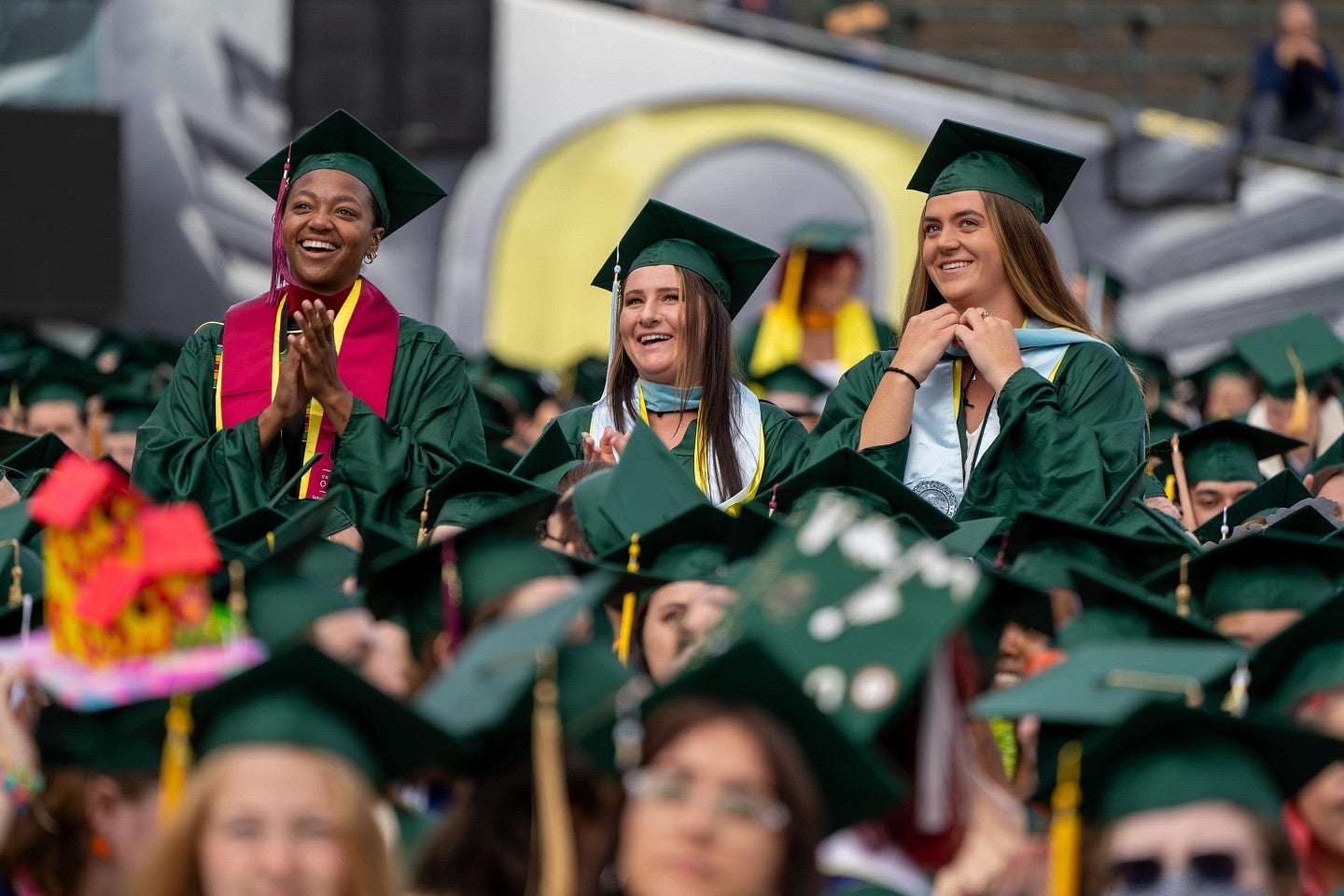 three women grads stand up