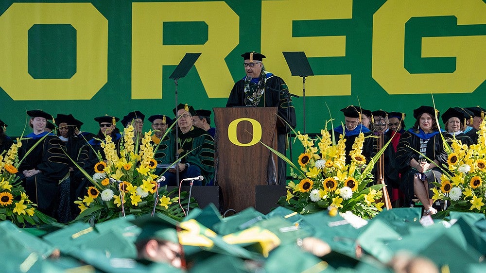 Jason Yonker speaking at the podium during UO commencement ceremony