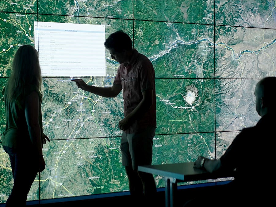 a researcher gestures to a large map of Oregon