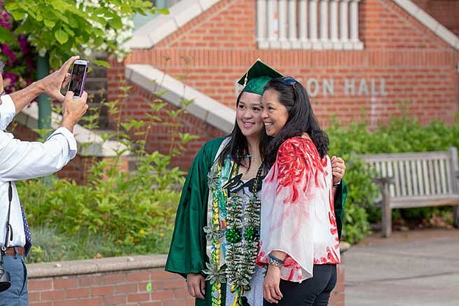 Families are all smiles taking photos with their graduates