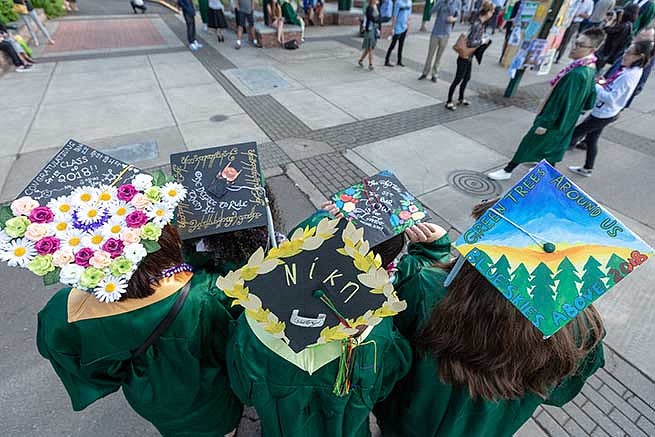Four students show off their decorated graduation caps