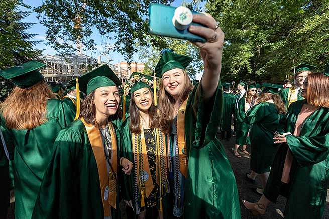 Students take a moment to get a selfie before parading down 13th avenue toward Matt Knight Arena