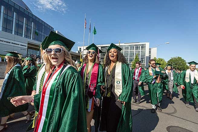 Students cheer for the camera before walking into the stadium for graduation