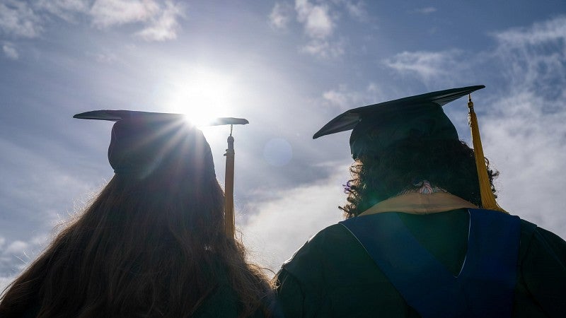 grad couple silhouetted against bright sun