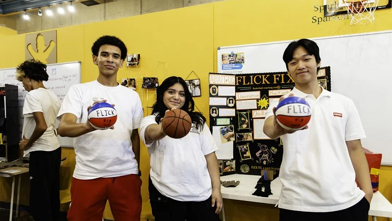 Several students show off their business idea, miniature red, white, and blue basketballs with custom branding,