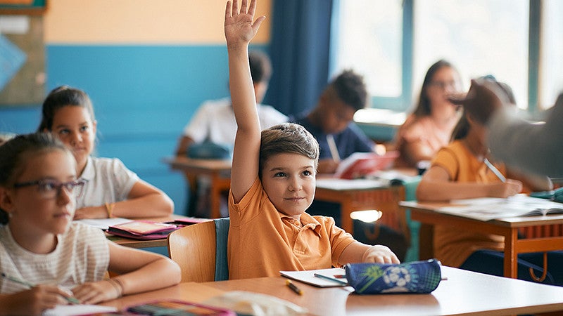 A child raising his hand in class