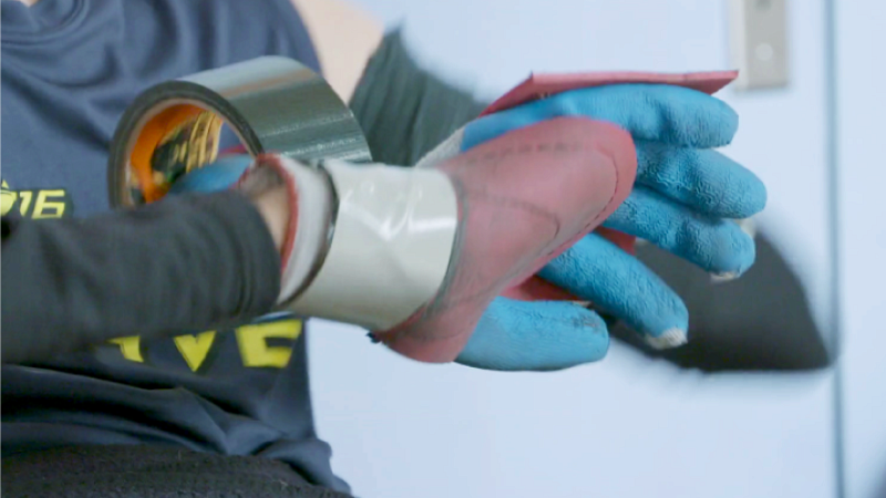 Seth McBride duct tapes garden gloves to his hands before wheelchair rugby practice