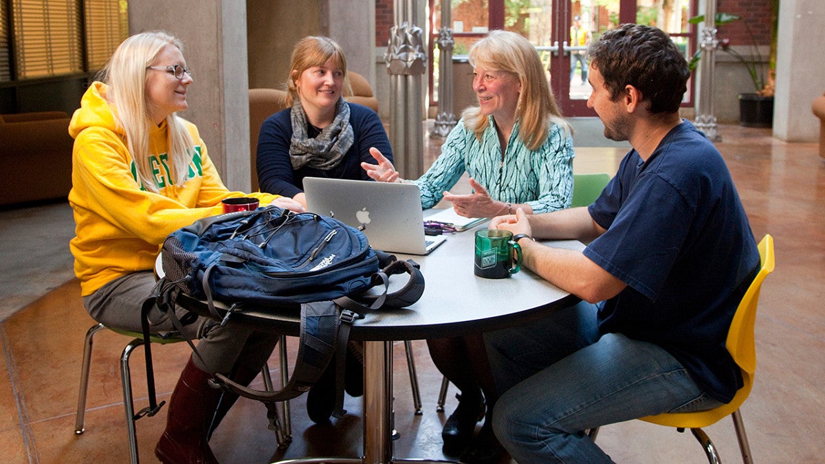 Geri Richmond talks with three students at a table
