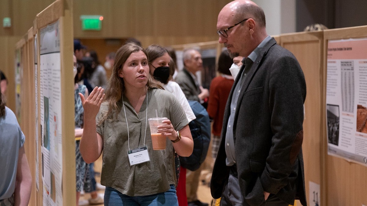 student discussing research poster with professor
