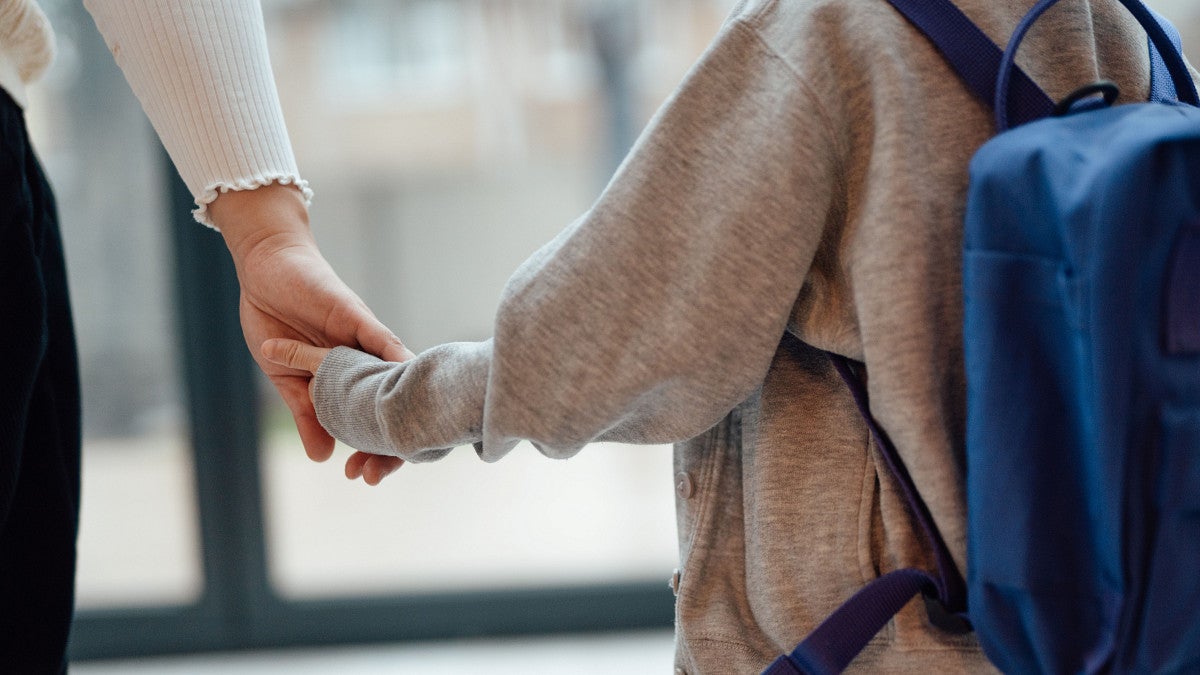 A child holds hands with an older person