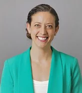 Elizabeth Day smiling wearing a turquoise jacket and a white shirt
