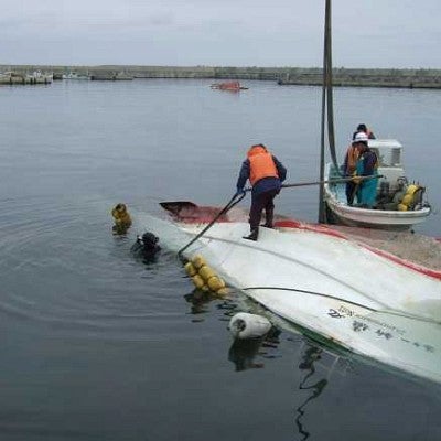 Workers attempt to right the Shinryu Maru No. 11, which was swamped by the tsunami. Photograph courtesy Misawa City Hall