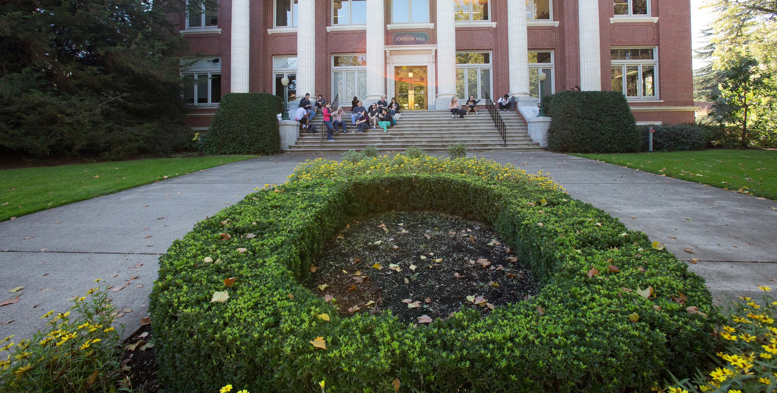 "O" shaped hedge and students on steps in front of Johnson Hall