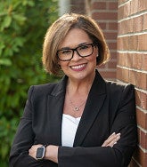 Jennifer Espinola smiling leaning against wall viewed from mid-chest up