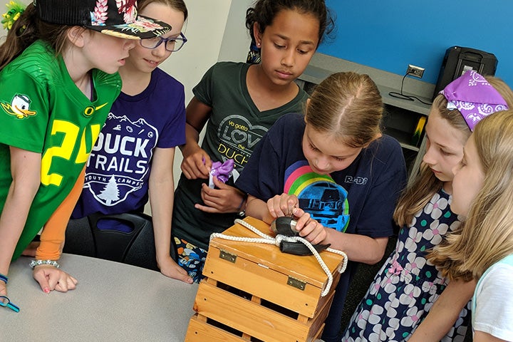 Group of children solving puzzles to receive keys to open locked box.