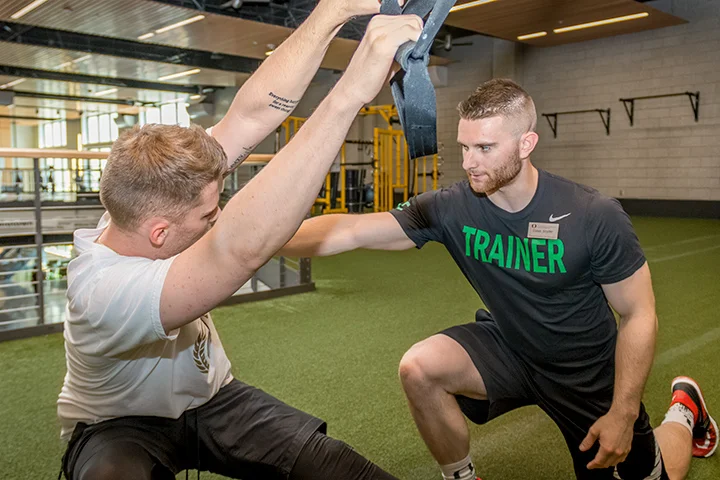 A personal trainer works with a student in the Fitness Yard.