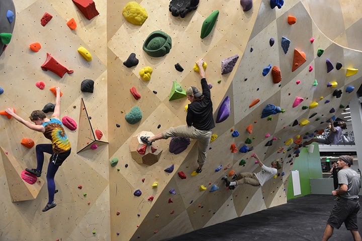 Four climbers navigating routes on the bouldering wall.