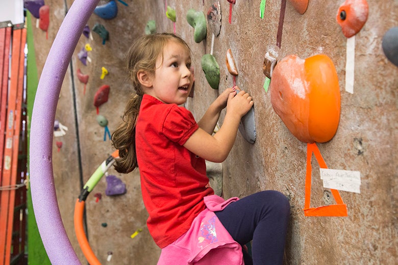 A young girl climbs on the bouldering wall.