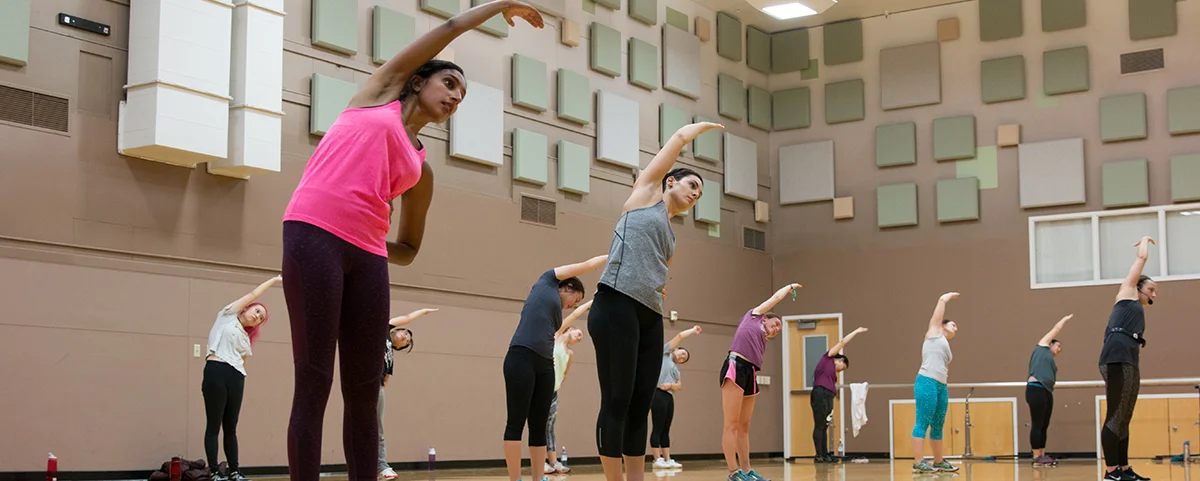 Several people stretching in large gymnasium.