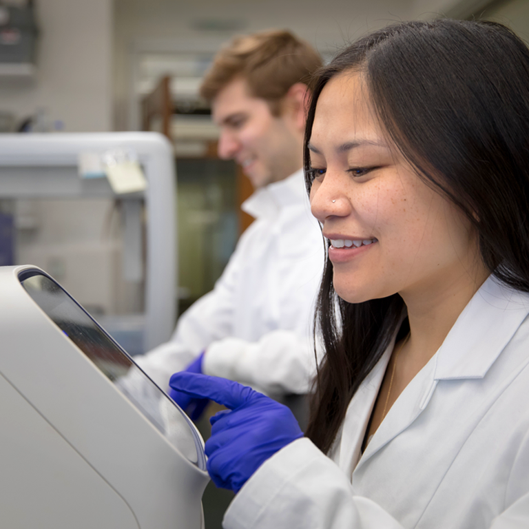 Woman and man in lab coats operating sequencing machinery.