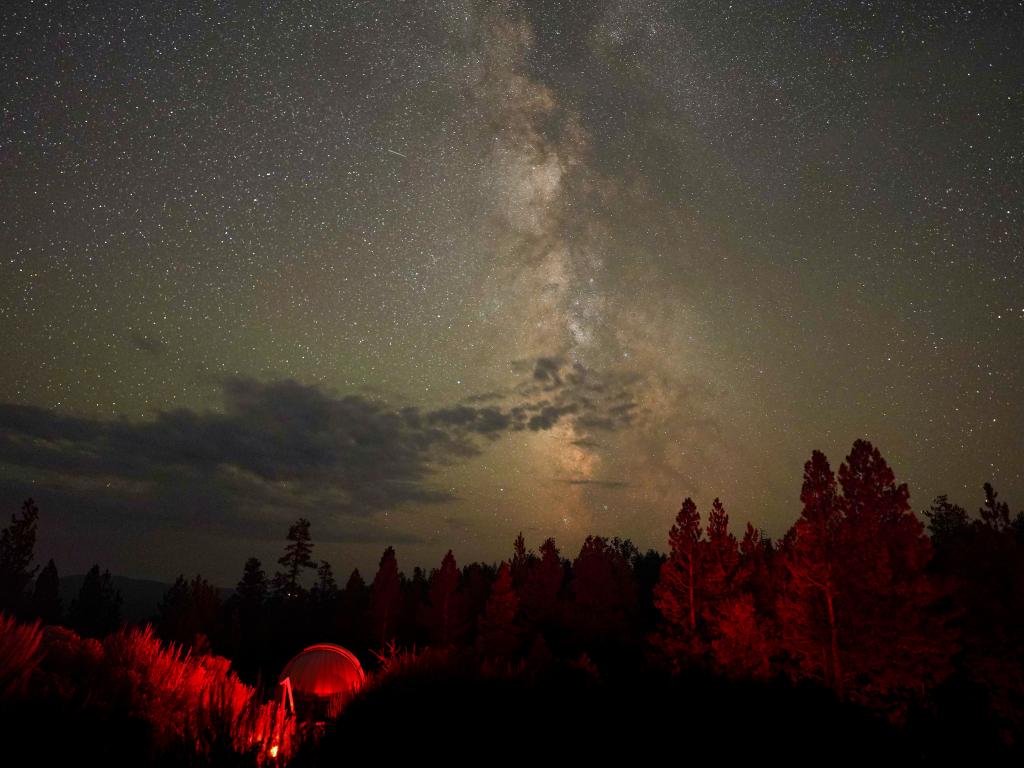 The Milky Way in the night sky above the red-lit dome of the Pine Mountain Observatory.