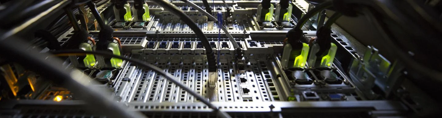 Wires coming out of a line of computer servers. 
