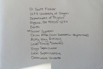 A handwritten "cosmic address" for Scott Fisher, listed from his address at the University of Oregon all the way to the observable universe.