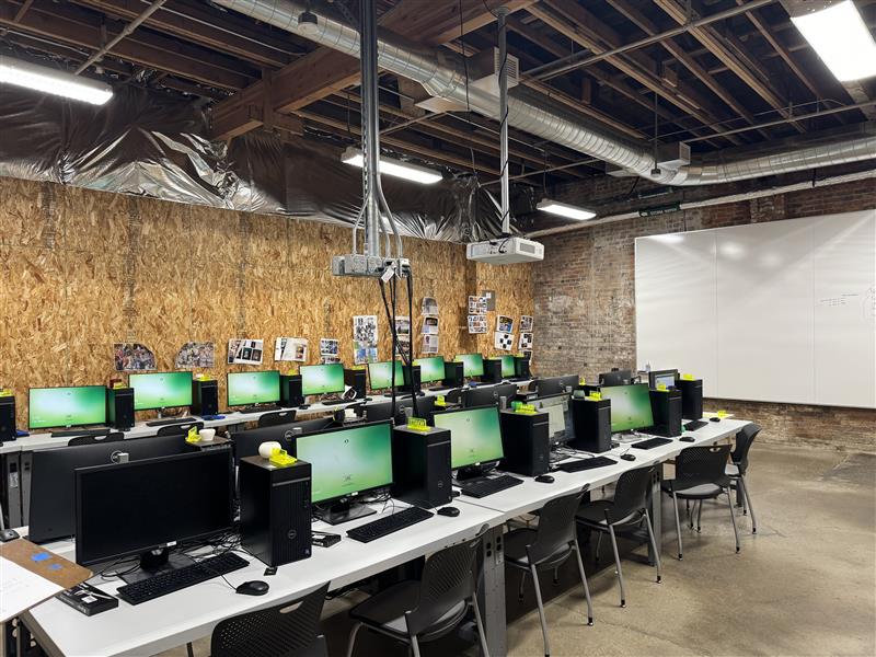 Image of Olive lab with whiteboard in background and computers on desks with plastic chairis