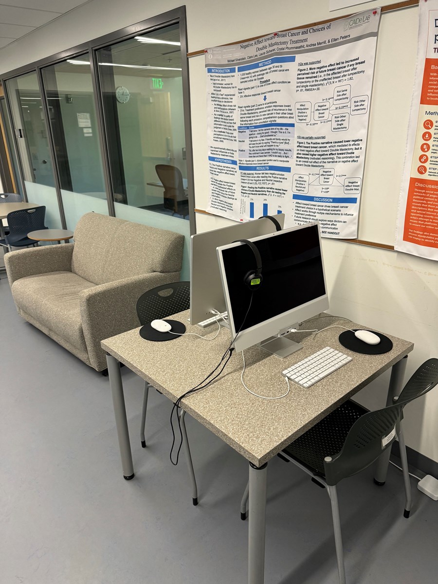 Image of two computers on a desk with a couch in the background