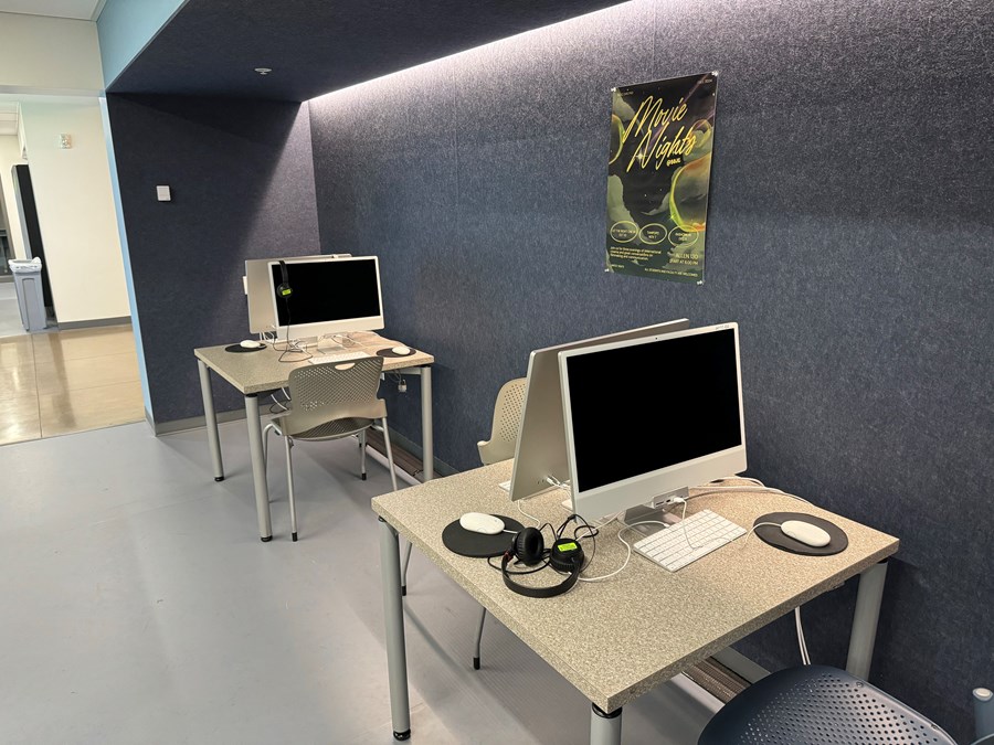 Image of four computers on desks in a nook of a hallway