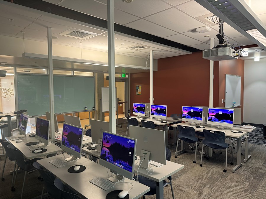 Allen 302 with computers on desks and a whiteboard on the back wall and the exit to its right